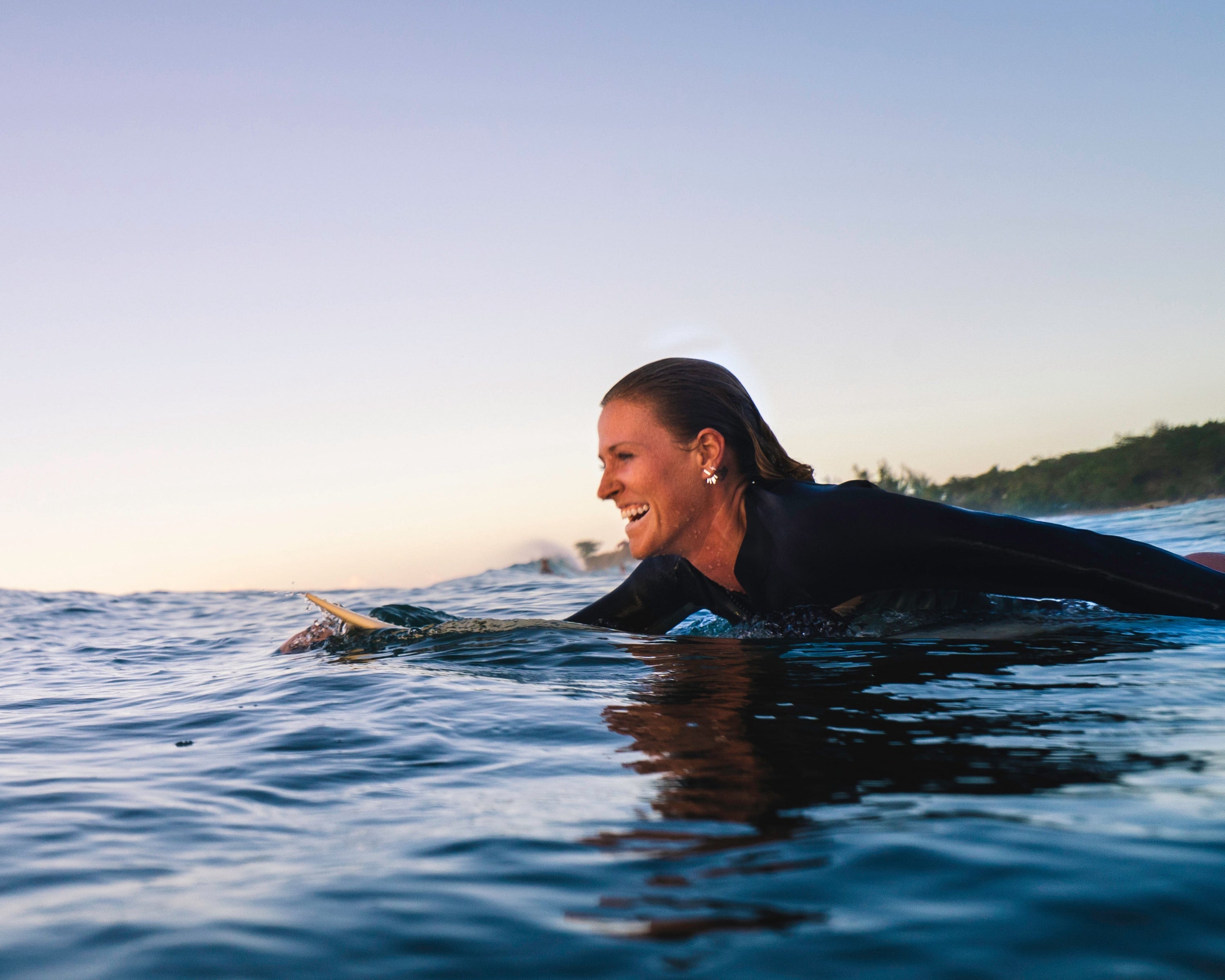 Cait paddling in the ocean on her surfboard