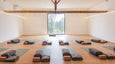 Casas Na Ferraria's light inside studio space with 12 PROlite yoga mats facing a large window in the front center of the room. each yoga mat has a bolster, cork block and blanket available for the yoga practice