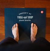 Person standing on a Manduka mat owned by Yoga Soup